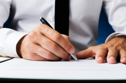 Wide view closeup image of businessman signing a document or contract.